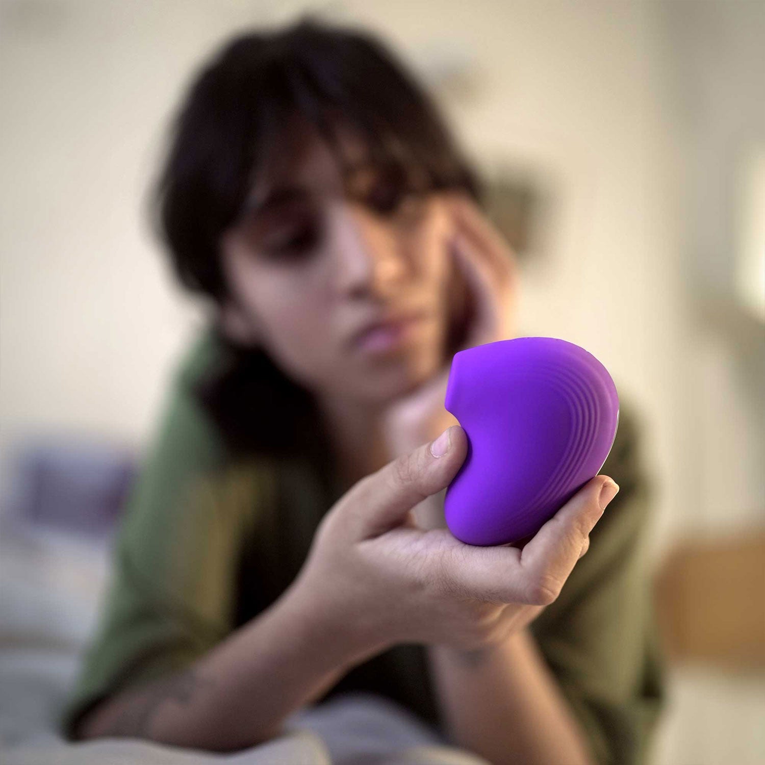 woman holding violet colored lit mini personal massager