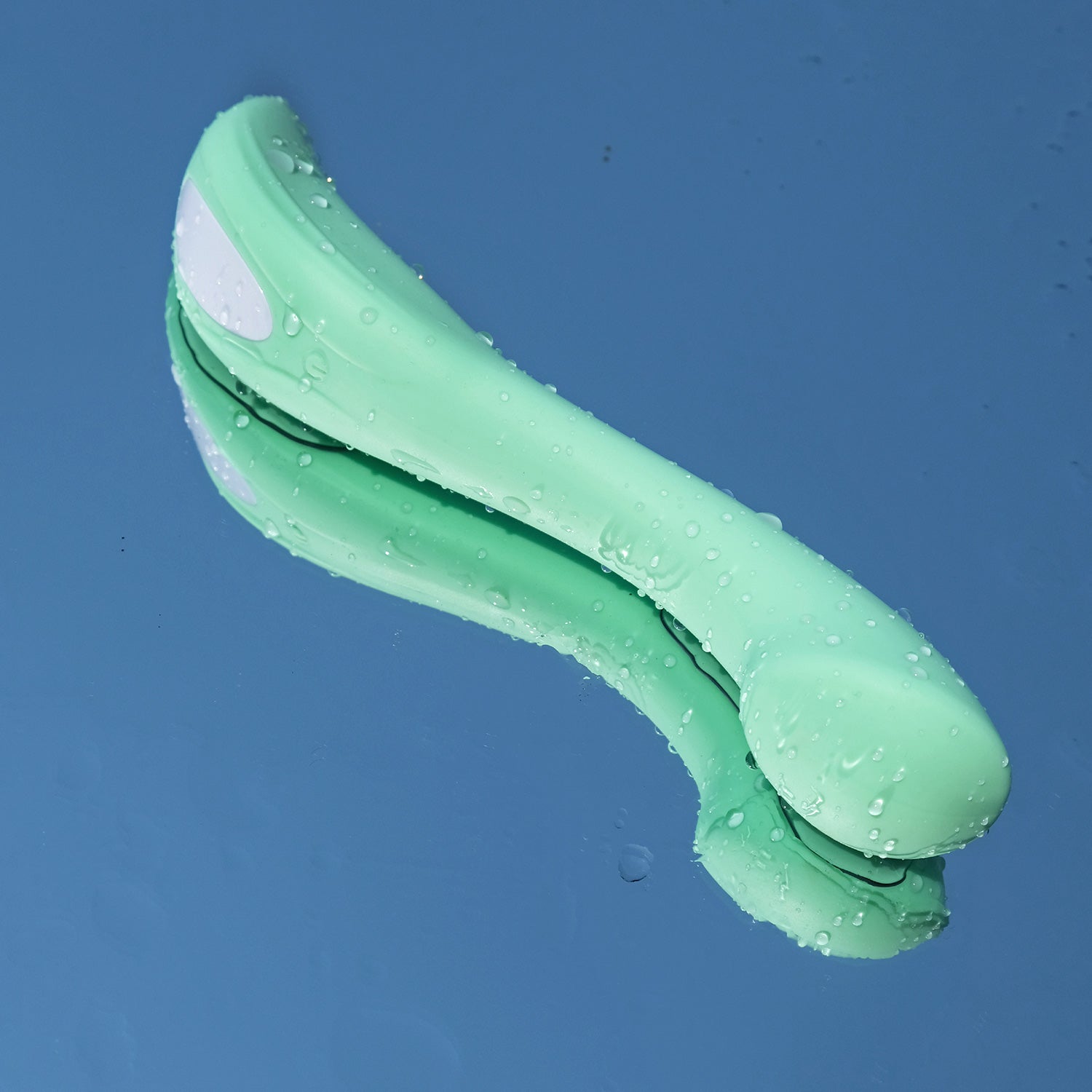 mint coloured og internal and external personal massager on wet surface