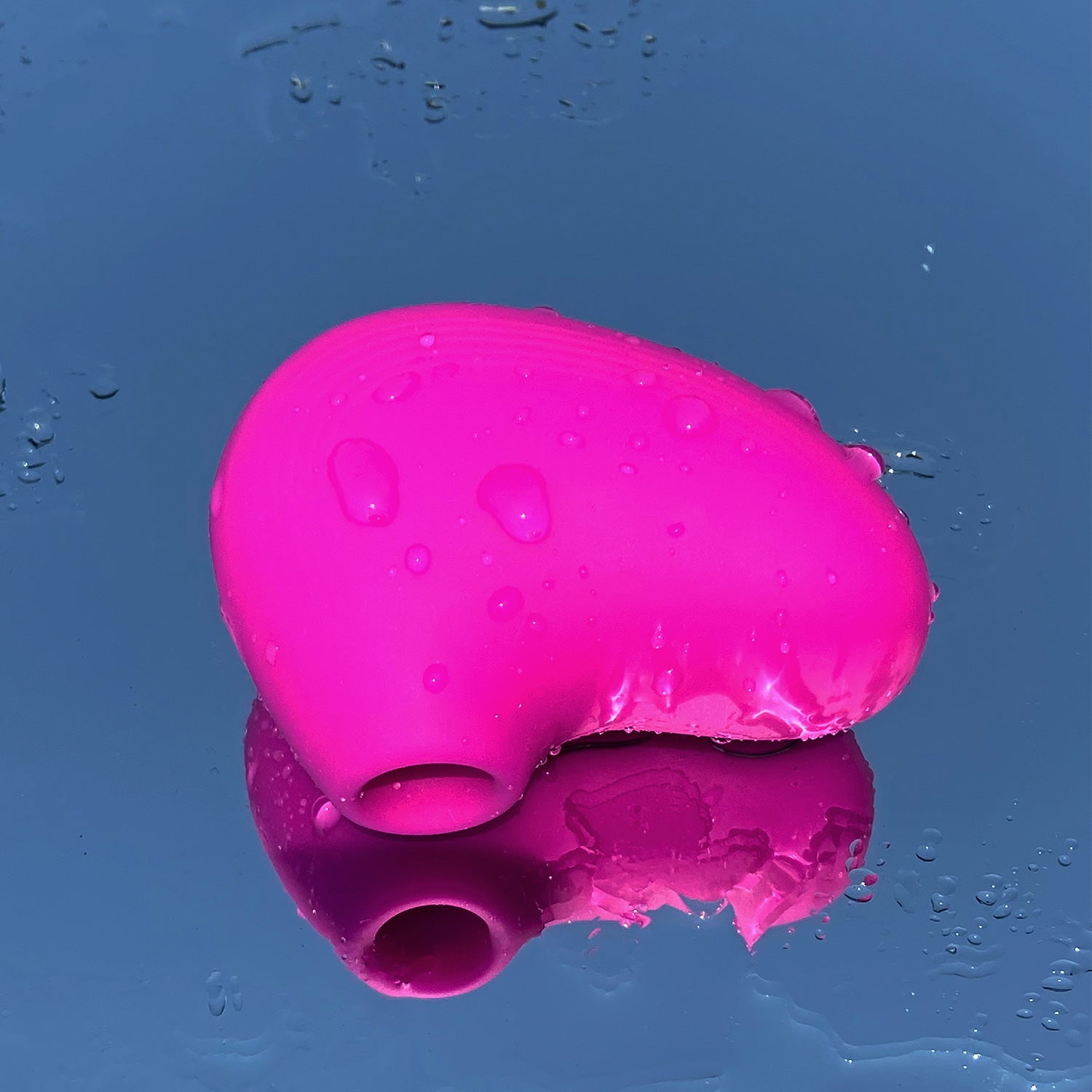 pink colored pocket-sized lit mini personal massager on wet surface