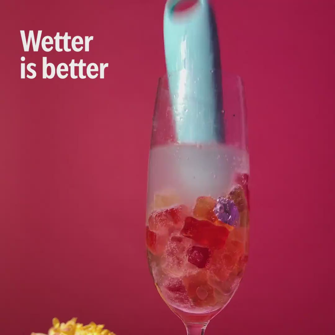 Blue Candy handheld massager in a glass with water and gummy bears, showing waterproof design.