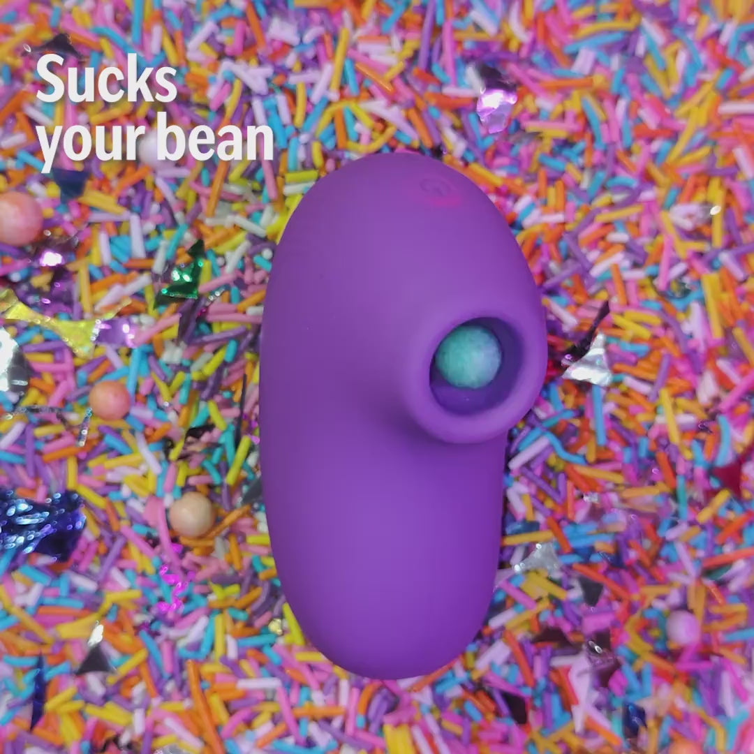 LIT suction massager in purple with bean demo on colorful sprinkles background.