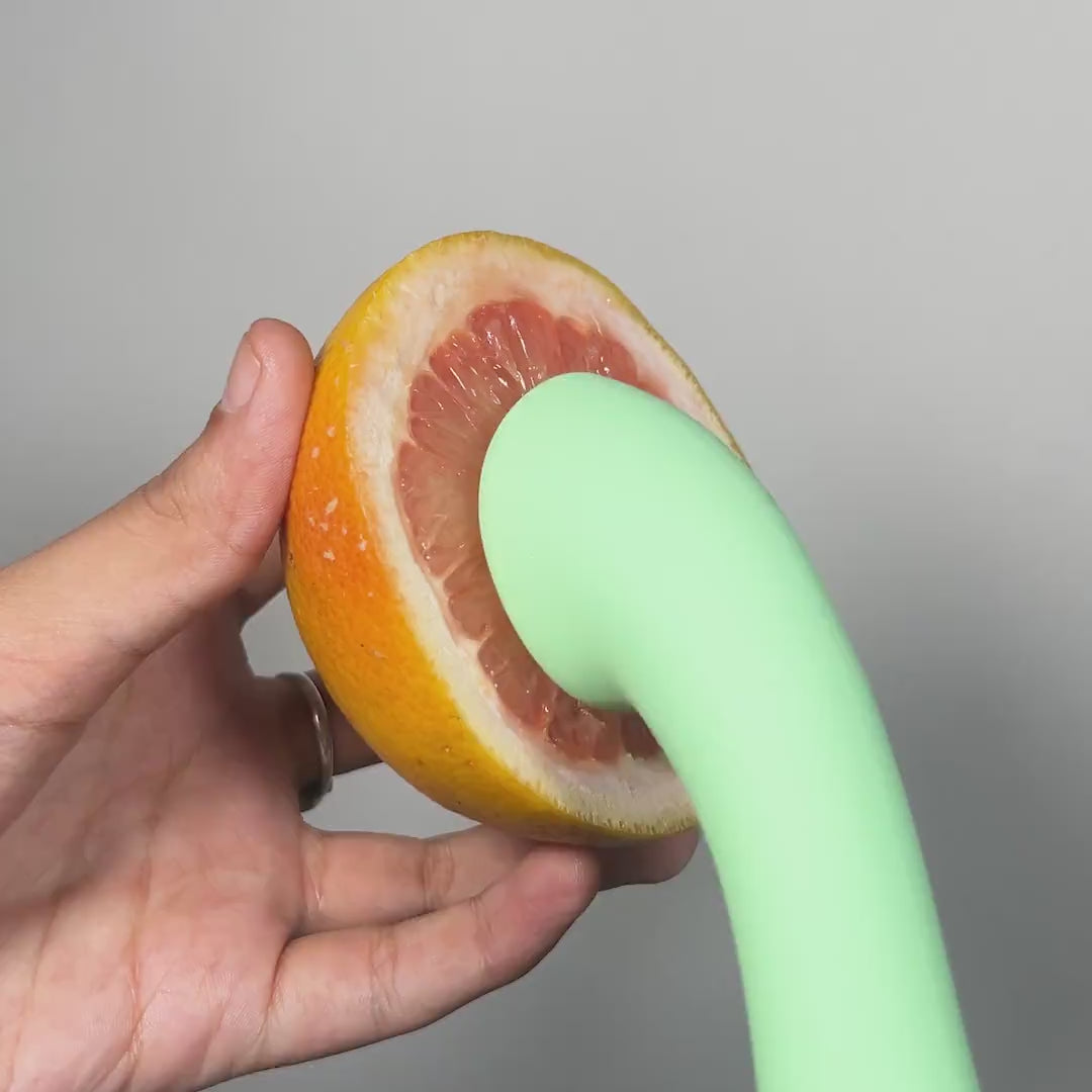 OG female massager shown with a fruit to highlight strong vibrations.