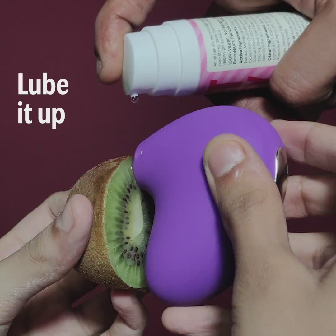 LIT suction massager in purple shown with lube and kiwi demo.