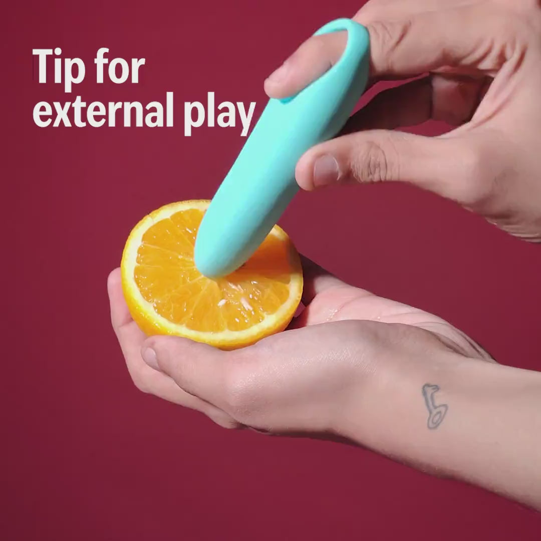 Blue Candy handheld massager used on an orange slice, showing tip for external play.