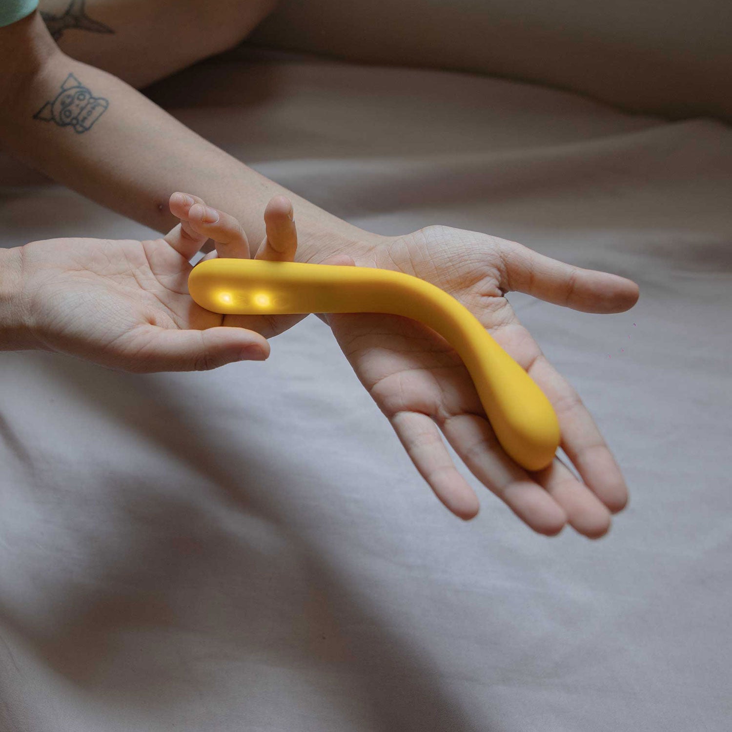woman's hand holding yellow colored flex internal massager