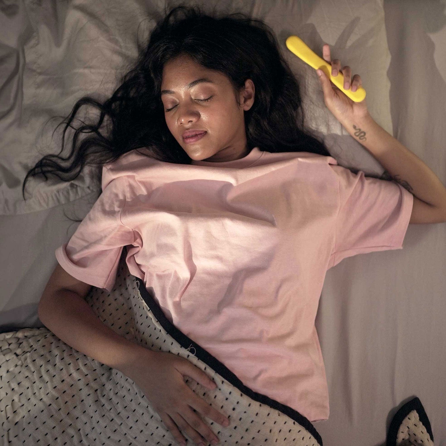 woman relaxing in bed with yellow colored flex internal massager
